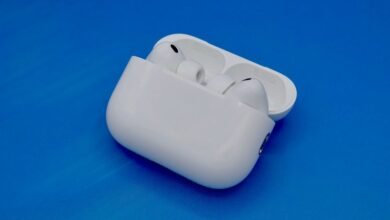 White Apple AirPods Pro earbuds in their charging case on a blue background.