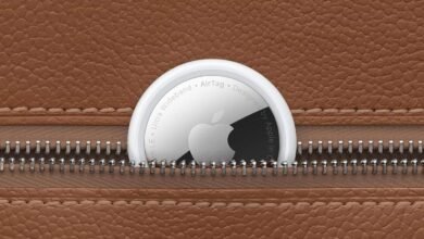 Apple AirTag with Apple logo partially visible, nestled in a brown leather case with a zipper.