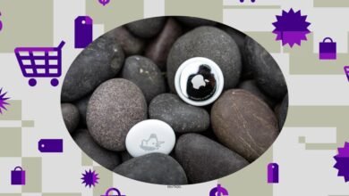 Two Apple AirTags resting on smooth, dark river stones, surrounded by shopping icons.