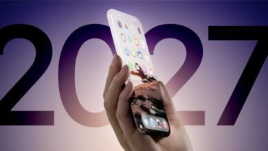 Hand holding a futuristic all-screen smartphone with a landscape wallpaper.