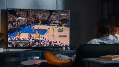 Man watching a basketball game on TV with advanced AI stats displayed.