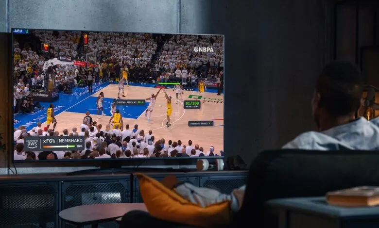 Man watching a basketball game on TV with advanced AI stats displayed.