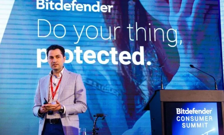 Man in a suit presenting on stage with Bitdefender branding behind him.