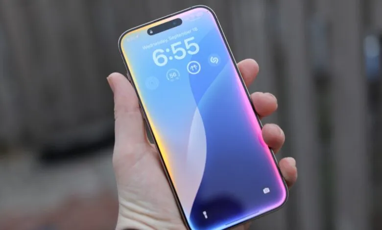 Close-up of a hand holding a smartphone displaying the time and date.