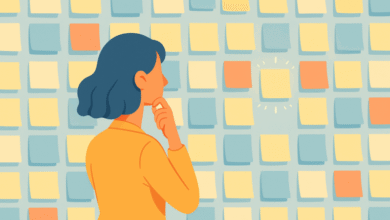 Woman in orange shirt looking at a wall of colorful sticky notes, one highlighted.