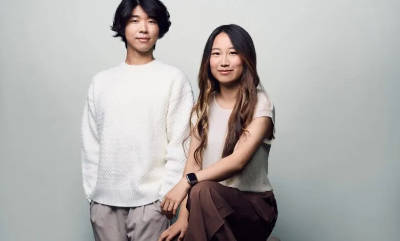 A young Asian man and woman posing for a studio portrait against a light gray background.