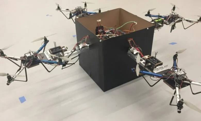 Four drones attached to a black cube, demonstrating coordinated flight and manipulation.