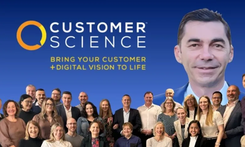 Team photo for Customer Science with a large portrait of a man above a group of diverse employees.