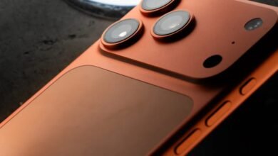 Close-up of an orange smartphone's rear camera array and side buttons.