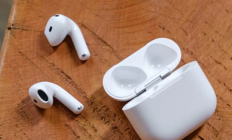 White wireless earbuds and charging case on a wooden surface