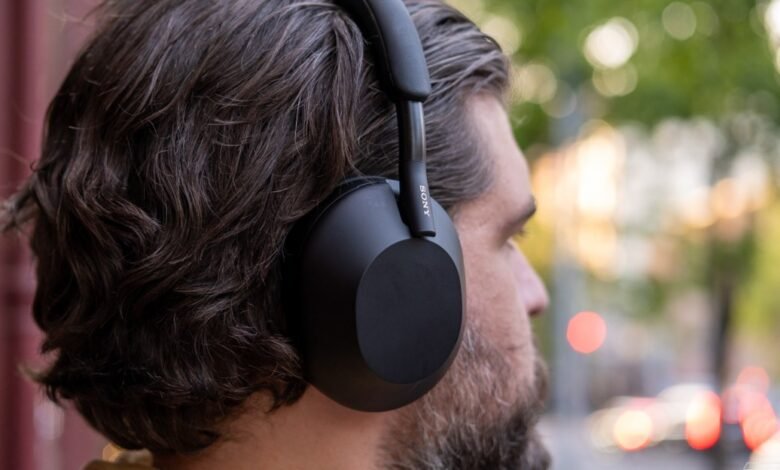 Close-up of a man wearing black Sony noise-canceling headphones outdoors.
