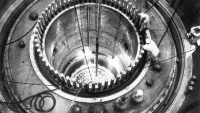 Workers in protective gear inspect the core of a nuclear reactor during construction.
