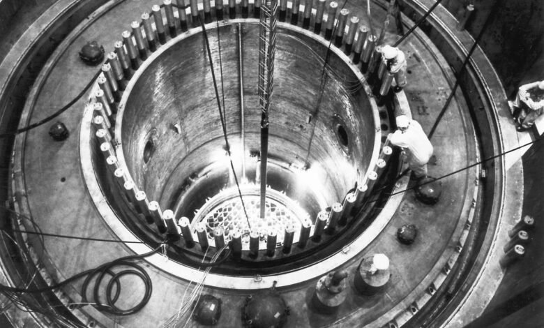 Workers in protective gear inspect the core of a nuclear reactor during construction.