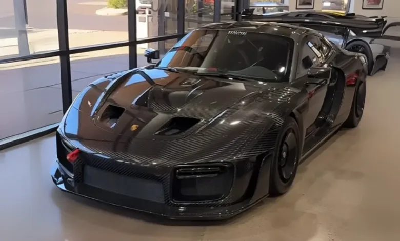 A black carbon fiber Porsche 935 sports car parked indoors.