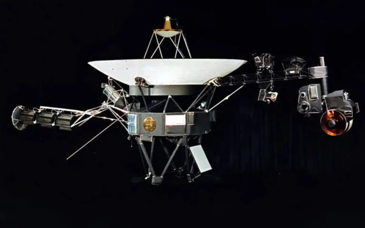Voyager 1 spacecraft with its large dish antenna and scientific instruments against a black background.