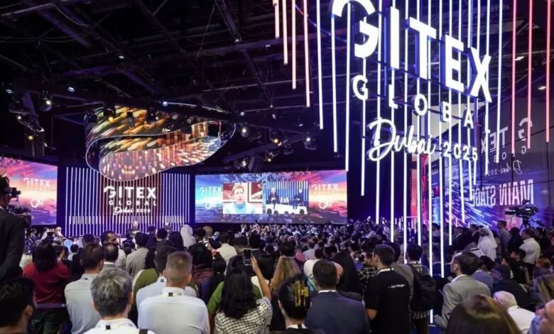 Crowd gathered at GITEX GLOBAL Dubai 2025 event with illuminated signage and stage screens.