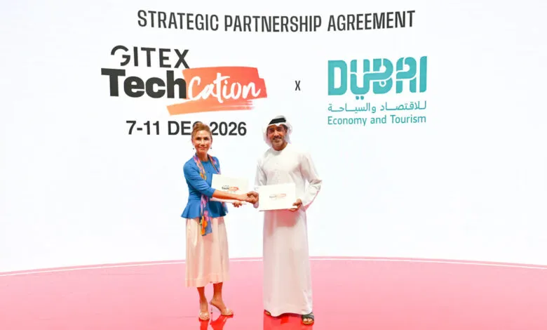 Two individuals shake hands while holding documents at a GITEX TechCation event.