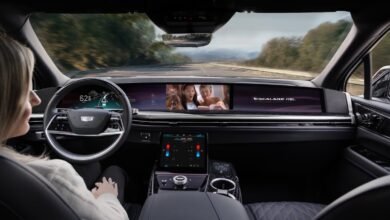 Interior view of a Cadillac Escalade IQ with a driver looking at the large curved display screen.