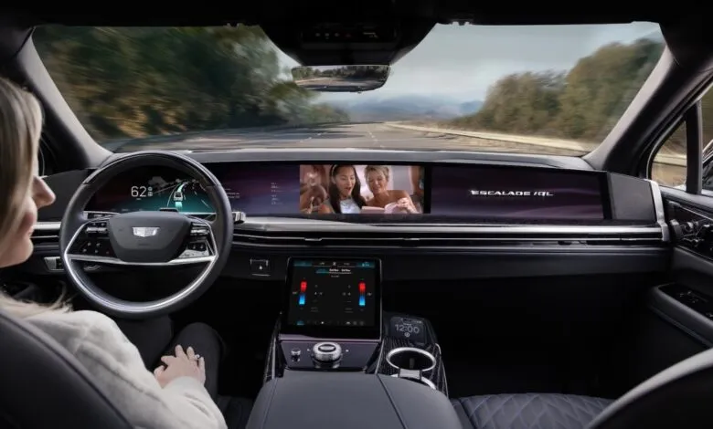 Interior view of a Cadillac Escalade IQ with a driver looking at the large curved display screen.