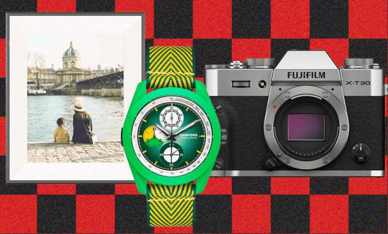 Framed photo of two people by a river, a green chronograph watch, and a Fujifilm camera.