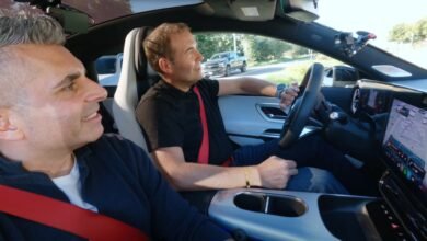 Two men in a car, one driving, with a dashboard display showing navigation.