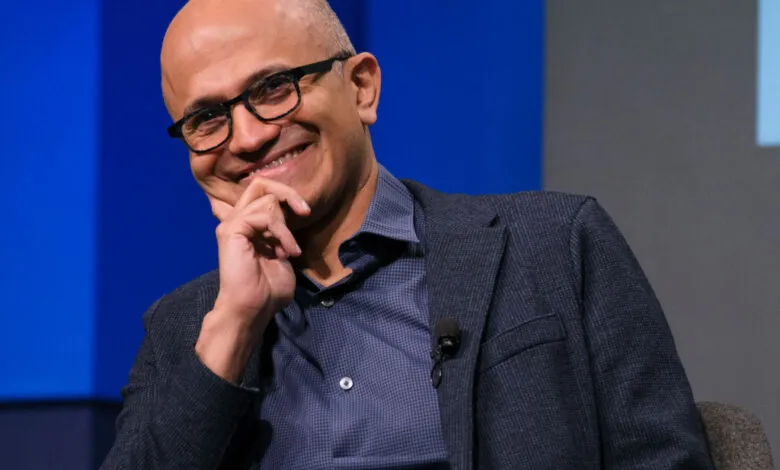 Microsoft CEO Satya Nadella smiles while resting his chin on his hand.