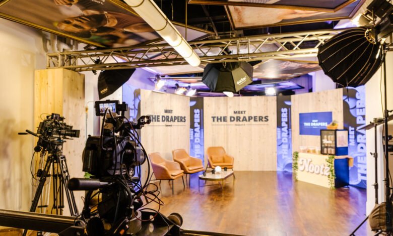Film set for 'Meet The Drapers' show with cameras, lighting, and branded backdrops.