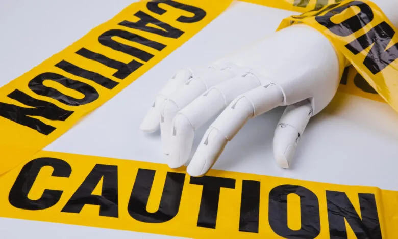 White robotic hand with yellow caution tape wrapped around it.