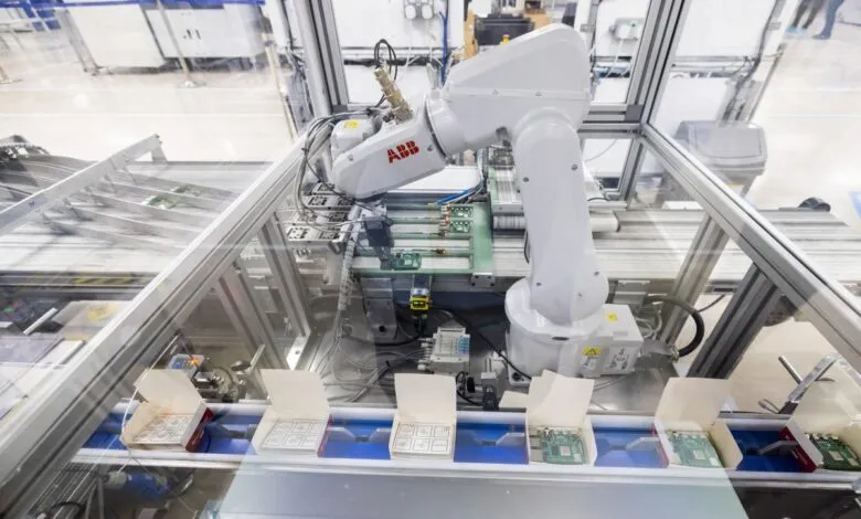 Automated robotic arm assembling electronic components on a conveyor belt in a factory.