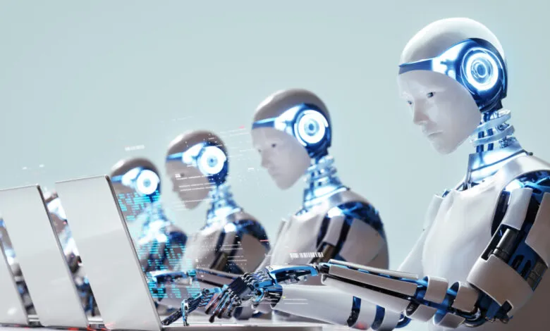 Row of humanoid robots with glowing blue eyes working on laptops.