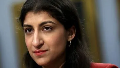 Close-up portrait of a woman with dark hair and brown eyes, wearing a red blazer.