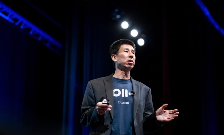 Sam Liang, CEO of Otter.ai, speaks on stage with a dark background and blue stage lighting.
