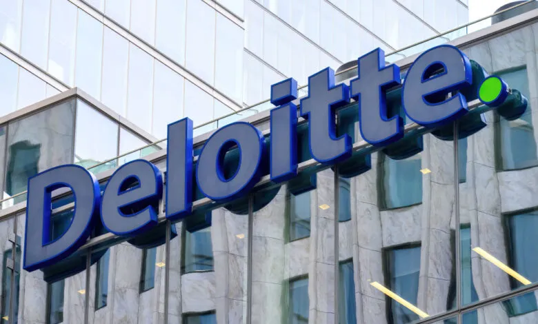 Large blue Deloitte logo mounted on a modern building with reflective glass facade.