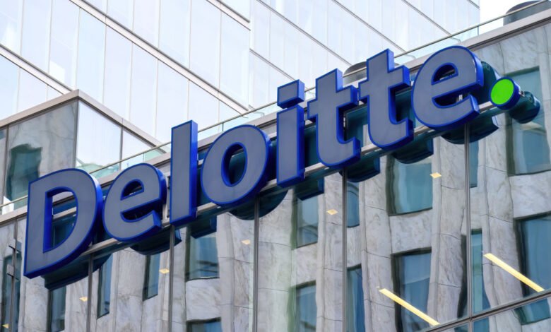 Close-up of the Deloitte logo on a modern building facade with reflective windows.