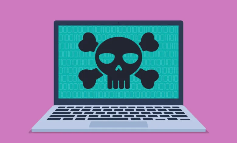 Laptop screen displaying a black skull and crossbones symbol over binary code.