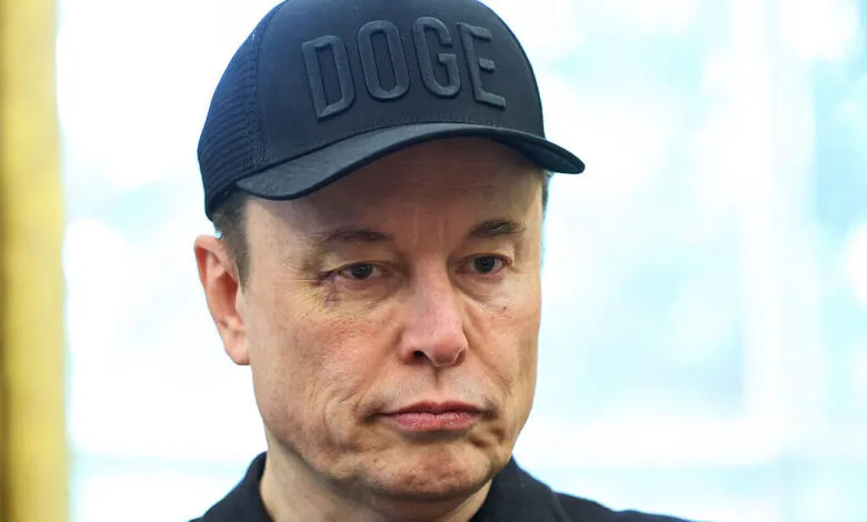 Close-up of Elon Musk wearing a black cap with 'DOGE' embroidered on it.