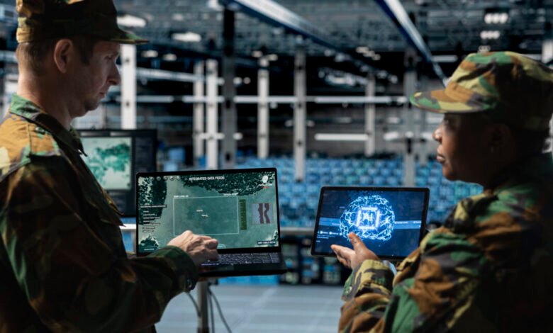 Two military personnel in camouflage uniforms analyze missile flight paths on digital displays.