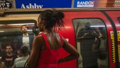 Woman in red dress holding a portable fan on a subway platform