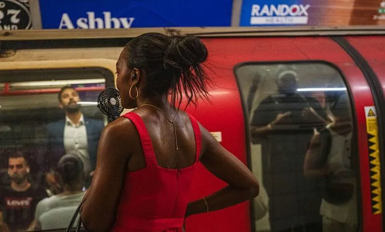 Woman in red dress holding a portable fan on a subway platform