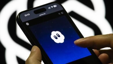A hand holds a smartphone displaying the OpenAI logo on a dark blue background with stars.
