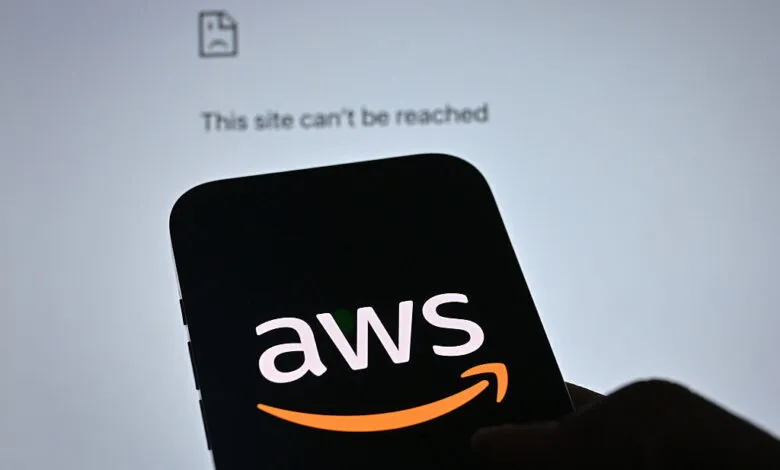 A smartphone displays the AWS logo with an error message 'This site can't be reached' on a computer screen.