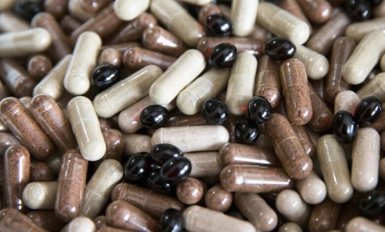 A close-up, overhead view of a large pile of assorted capsules and pills.