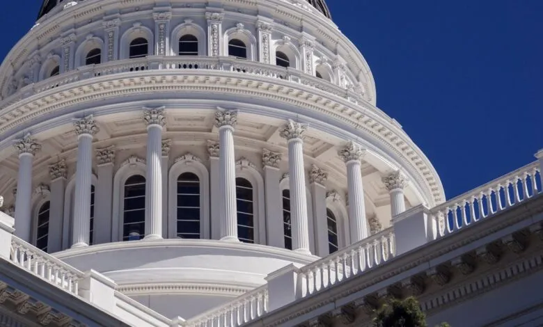 Close-up of the white dome and columns of a capitol building against a clear blue sky.