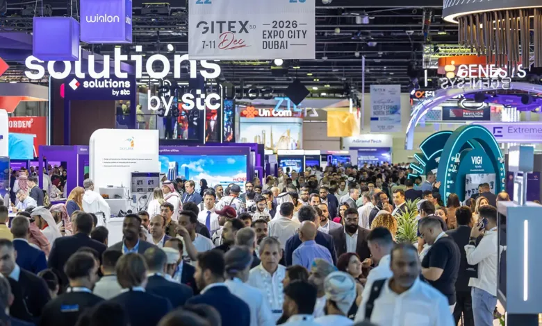 Crowded exhibition hall with many attendees and booths, featuring large signs for GITEX and various tech companies.
