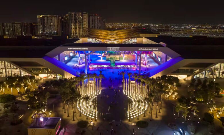 Aerial view of Dubai Exhibition Centre at night with illuminated palm trees and modern architecture.