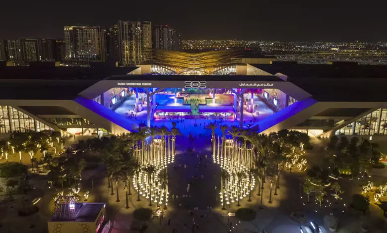 Aerial view of Dubai Exhibition Centre at night with illuminated palm trees and modern architecture.