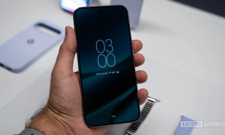 Close-up of a hand holding a smartphone displaying its always-on screen with the time and date.