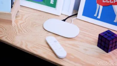 White Google TV remote and streaming device on a wooden surface