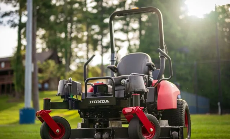 Close-up of a red and black Honda zero-turn lawn mower parked on a green lawn.