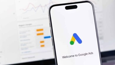 Smartphone displaying the Google Ads logo and welcome message, with a blurred analytics graph in the background.